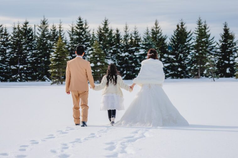 Couple and kid are walking their own path through fresh snow during a winter photo shoot in Hokkaido