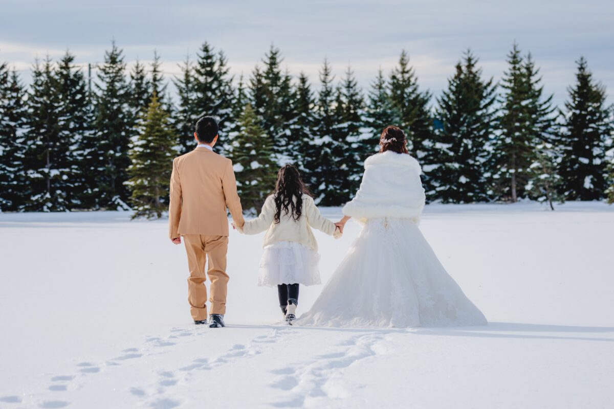 A couple and their daughter walking their own path through fresh snow during a winter photo shoot in Hokkaido